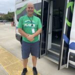 a man in a green shirt is standing in front of an oven