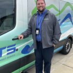 a man standing next to a green and white truck