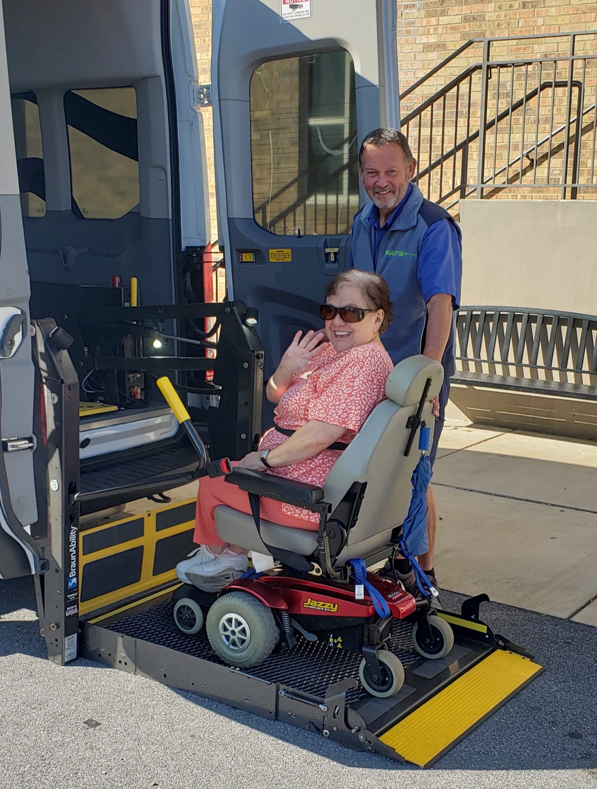 a man standing next to a woman in a wheel chair